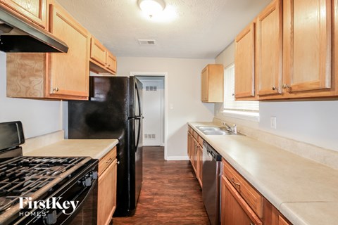 A kitchen with wooden cabinets and a black fridge.
