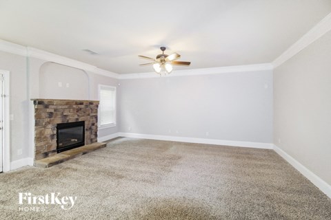 the living room has a stone fireplace and a ceiling fan