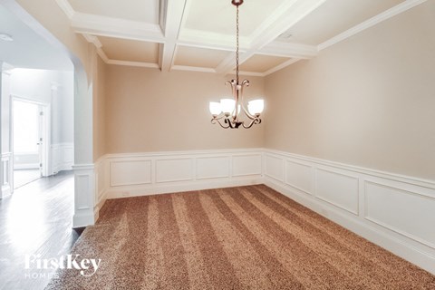 a dining room with a carpet and a chandelier