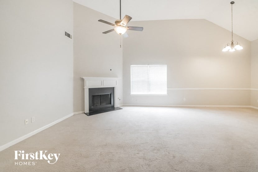 an empty living room with a ceiling fan and a fireplace