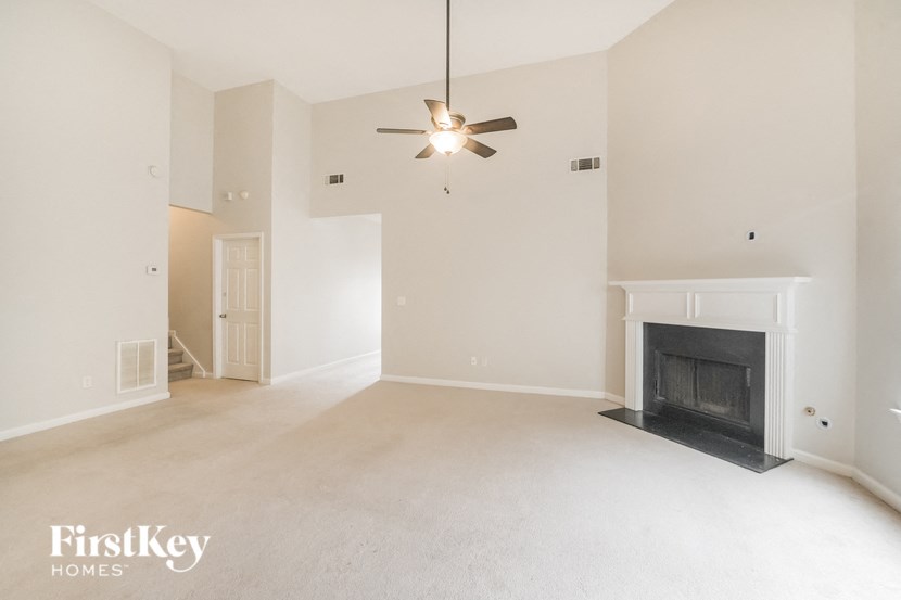 an empty living room with a fireplace and a ceiling fan