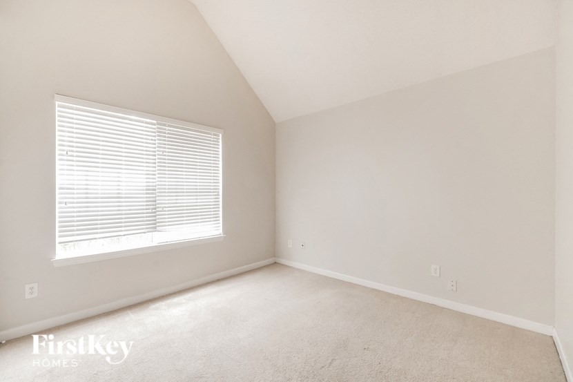a bedroom with a large window and a carpeted floor