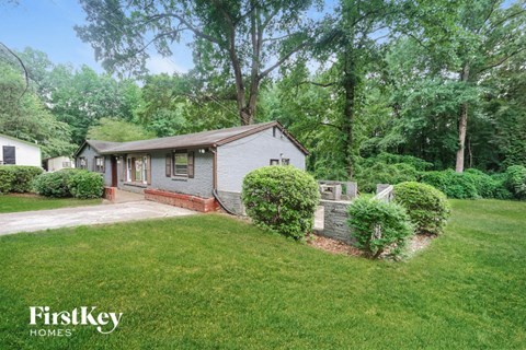 a small white house with a yard and a driveway
