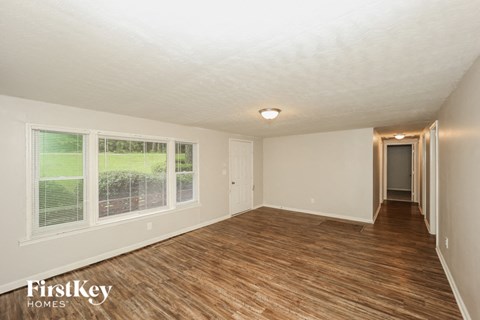 the living room and hallway of an empty house with wood flooring