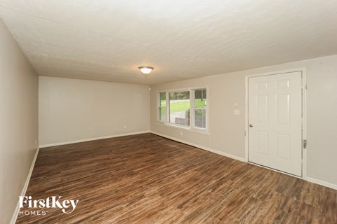 the living room of an empty house with wood flooring and a white door