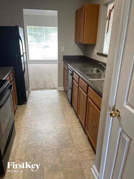 A kitchen with a black fridge and wooden cabinets.