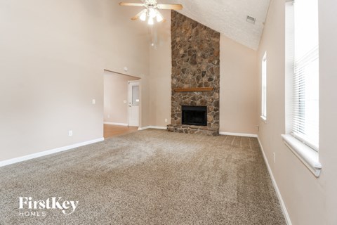 a carpeted living room with a fireplace and a ceiling fan