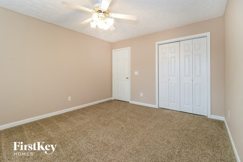 an empty bedroom with a ceiling fan and two doors