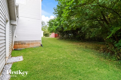 the backyard of a white house with a yard and trees