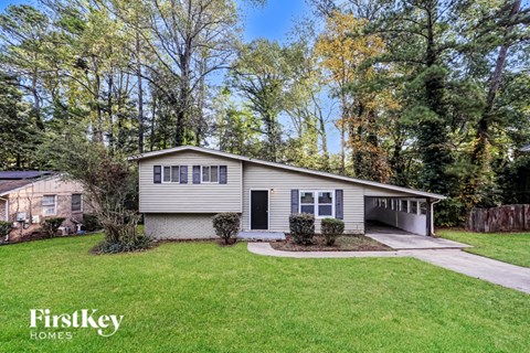a white and blue house with a lawn and trees
