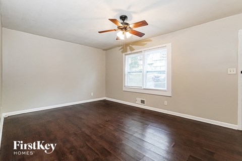 the living room of a home with wood floors and a ceiling fan