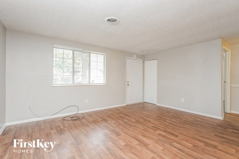 a living room with wood floors and white walls and a window