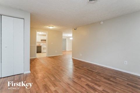 the living room and dining room of an apartment with wood flooring and white walls