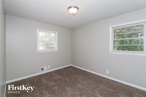 a bedroom with a carpeted floor and two windows