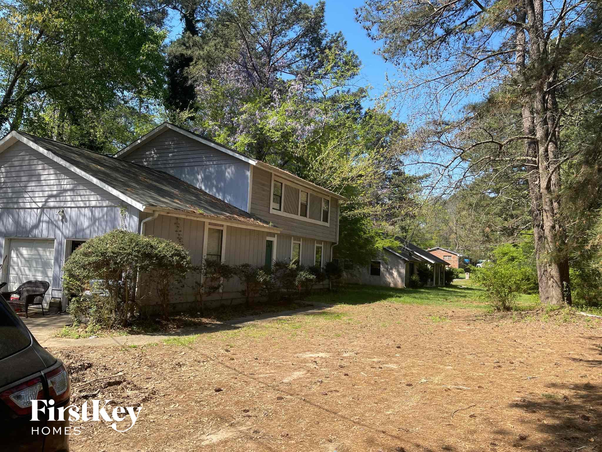 a house in the woods with a dirt driveway