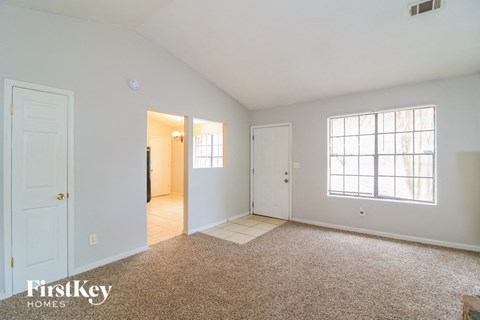 A sparsely furnished room with a carpeted floor and a window letting in natural light.