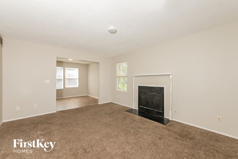 A spacious living room with a fireplace and carpeted floor.