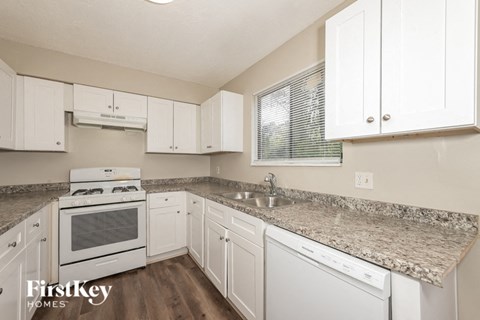 A kitchen with white cabinets and a granite countertop.