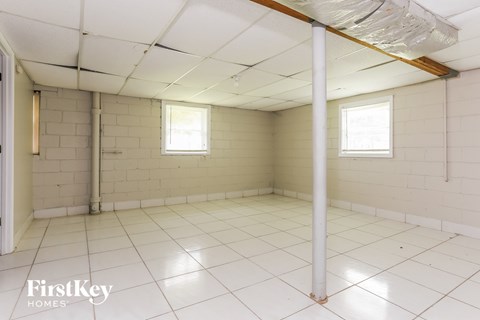 an empty room in a building with white tiled floors and walls and two windows