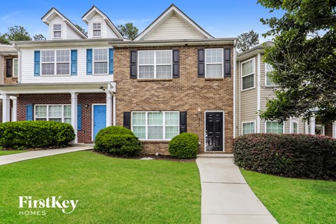 A brick house with a blue door and a sign that says FirstKey Homes.
