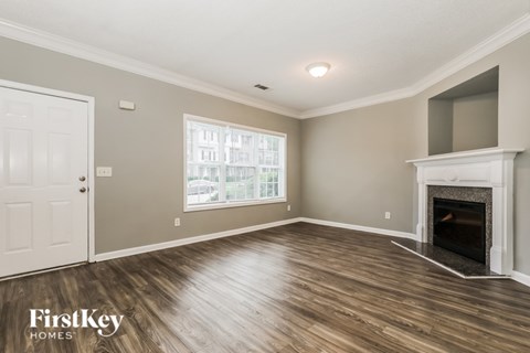 A spacious living room with a fireplace and a large window.