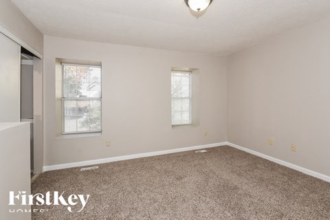 a spacious room with carpet and two windows