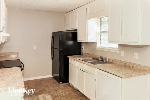 A kitchen with a black refrigerator and white cabinets.