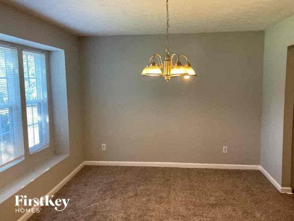 an empty dining room with a chandelier and a window