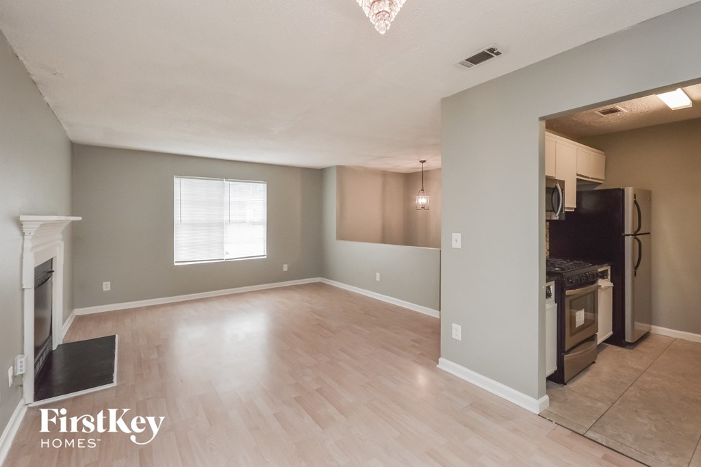an empty living room and kitchen with a wood floor