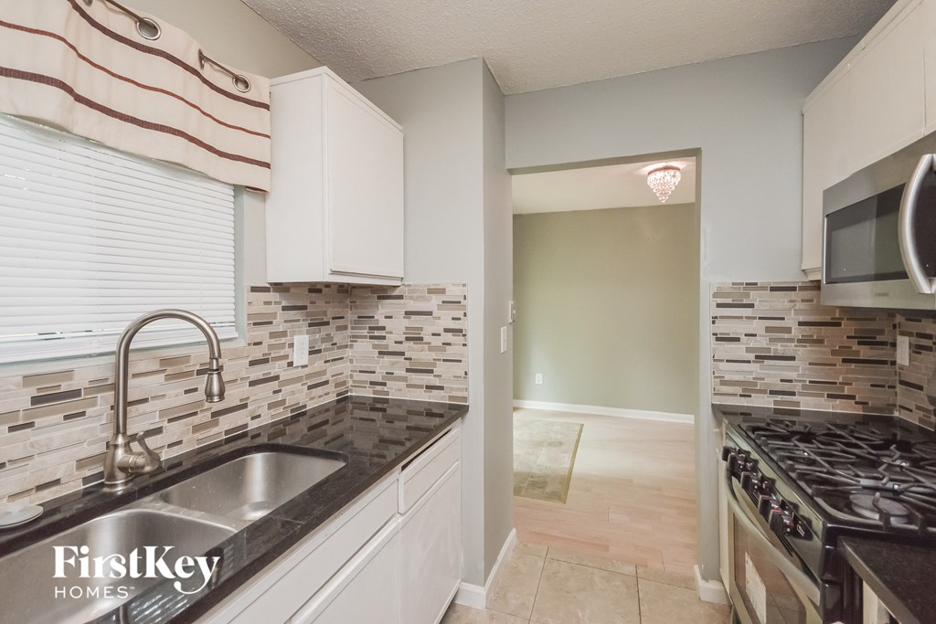 a kitchen with white cabinets and a sink and a stove