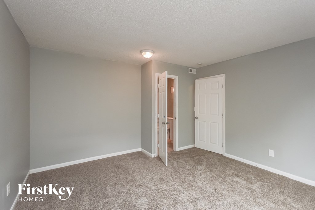 a bedroom with a door to a closet and a carpeted floor