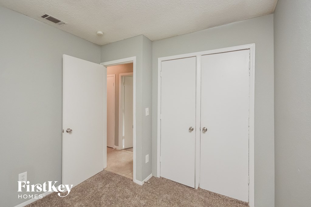 a bedroom with white closets and a carpeted floor