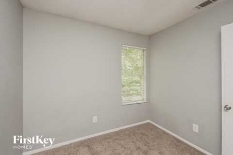 the living room of an apartment with carpet and a window