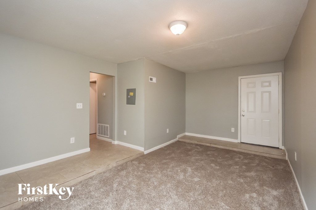 the spacious living room with carpeted flooring and a white door