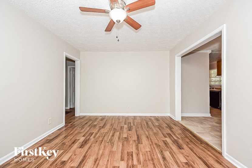 an empty living room with a ceiling fan and wood floors