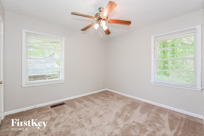 an empty bedroom with a ceiling fan and two windows