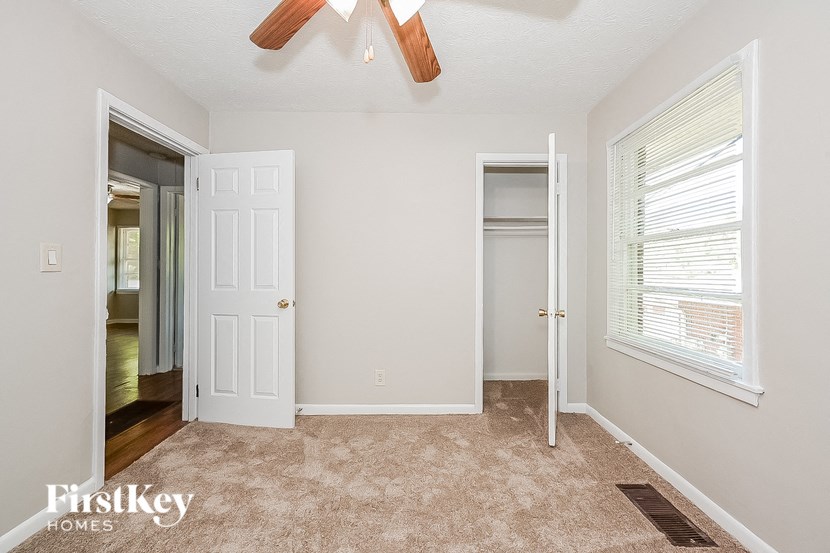 an empty bedroom with a ceiling fan and a closet