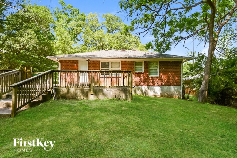 a small red brick house with a porch and a deck