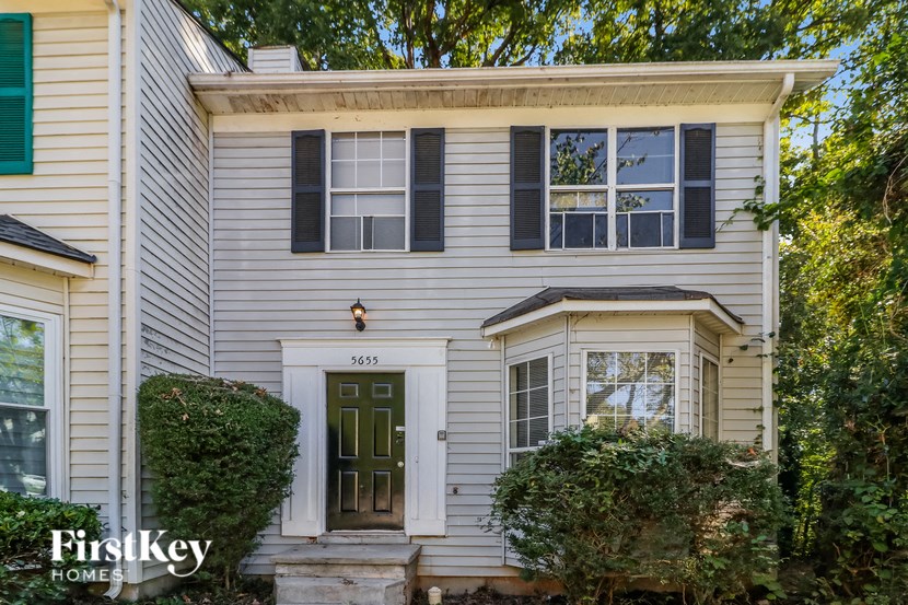 a white house with black shutters and a green door