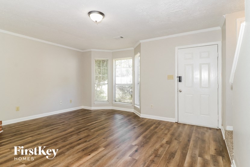 an empty living room with a white door and wood floors