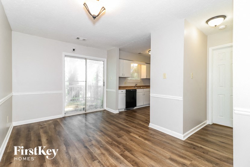 an empty living room and kitchen with wood flooring