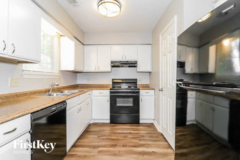 a kitchen with white cabinets and black appliances