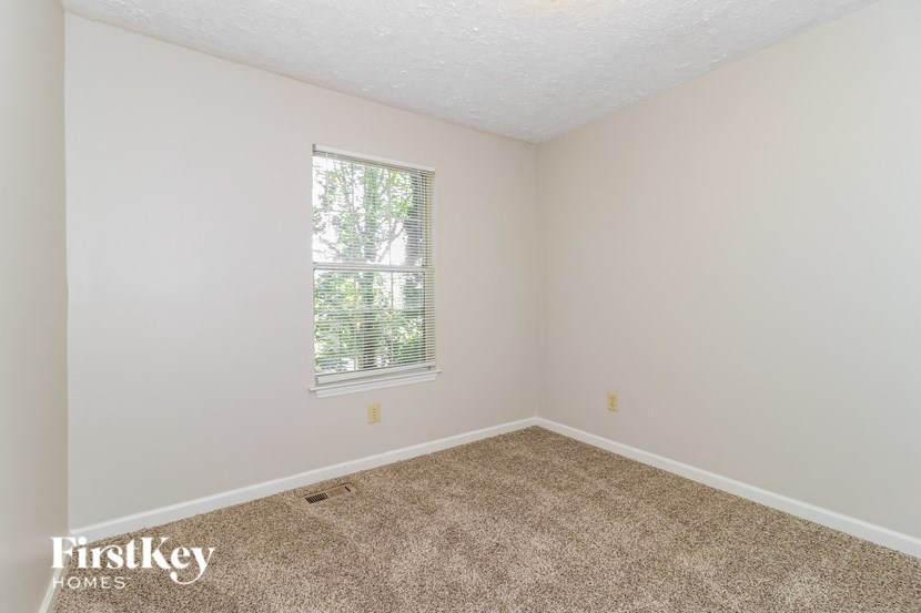 the bedroom of a home with carpet and a window