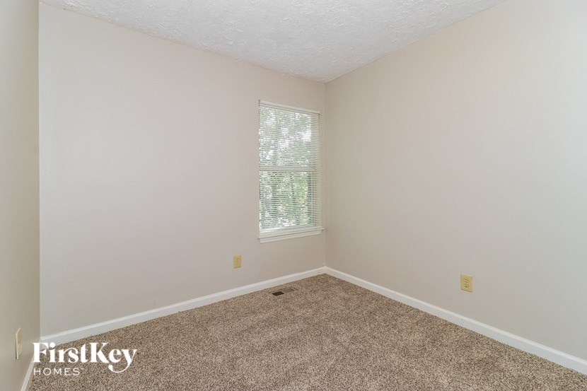 the bedroom of a home with carpet and a window