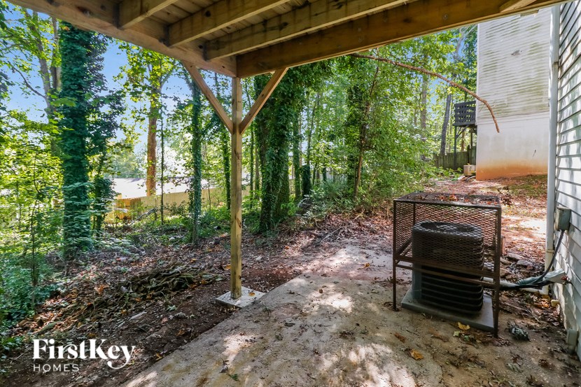 the back porch of a house with a grill and trees