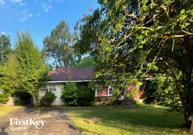 a house with a driveway and trees in front of it