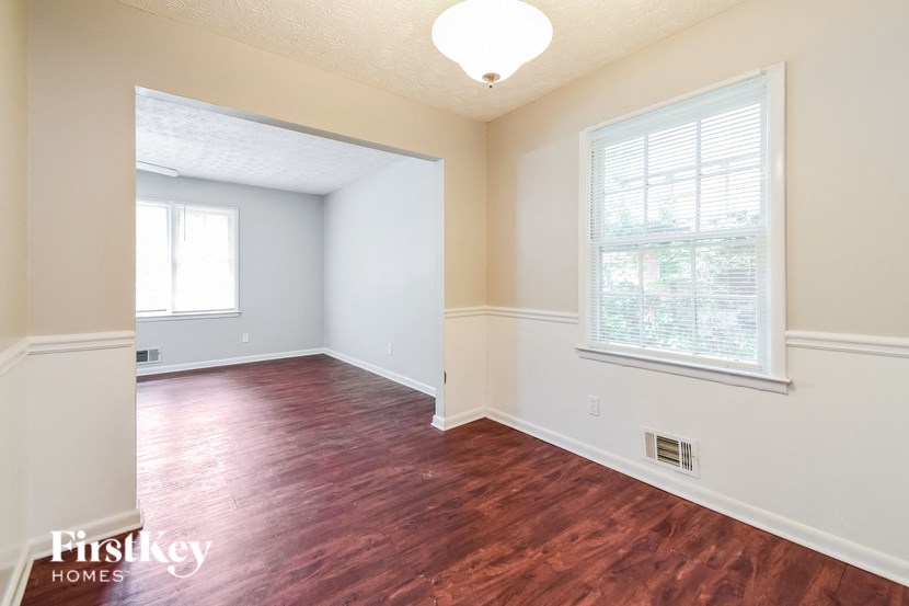 A room with wooden floors and a window with blinds.