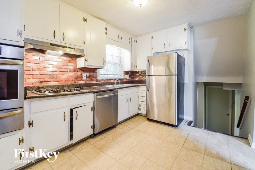 A kitchen with white cabinets and a brick backsplash.