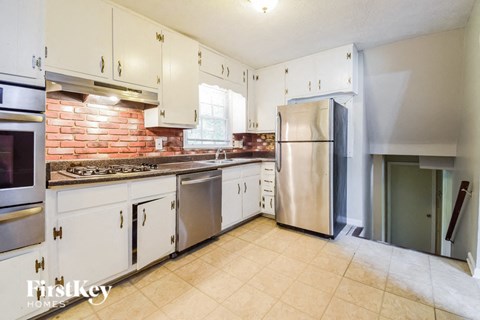 A kitchen with white cabinets and a brick backsplash.