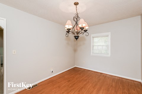 A room with a wooden floor and a chandelier hanging from the ceiling.